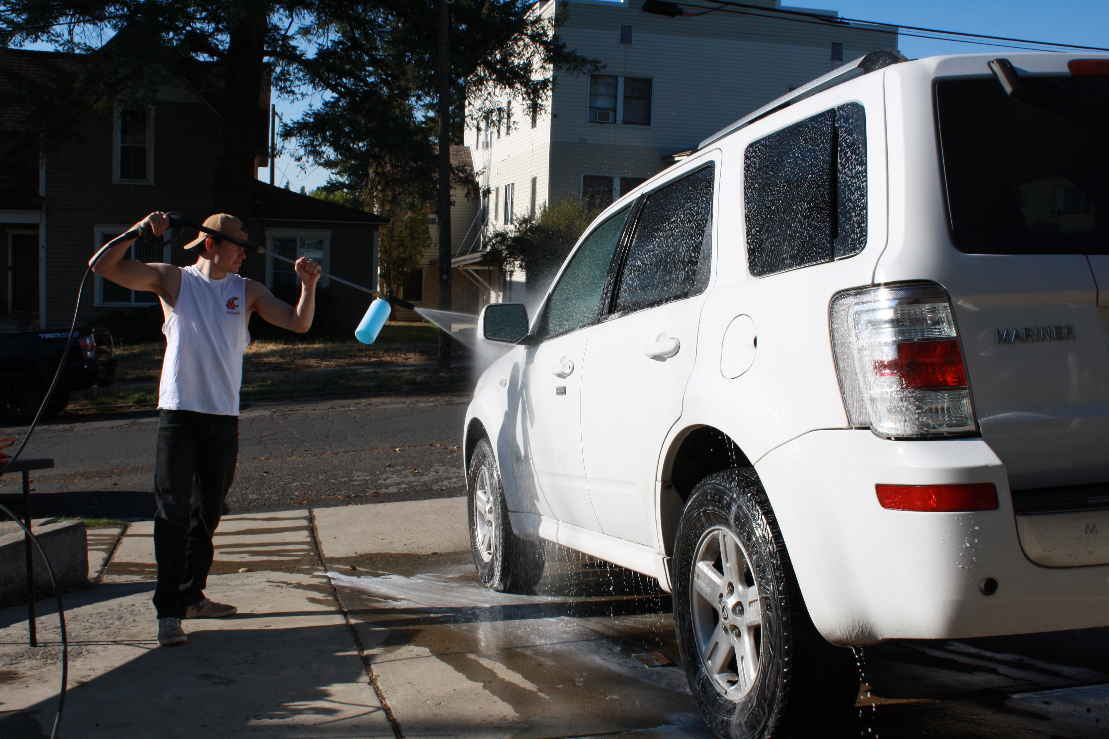 Professional pressure washing process on white SUV